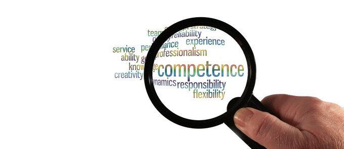 Durch den Blick einer Lupe sind Begriffe, wie competence, responsibility und flexibility zu sehen.